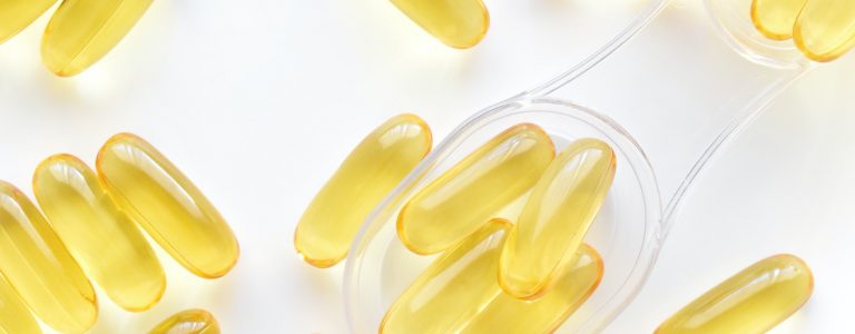 Fish oil supplement capsules on spoon.